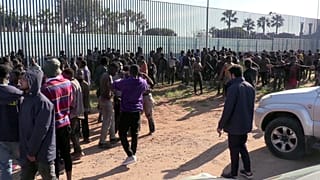 Menschen vor dem Zaun an der Grenze zu Melilla