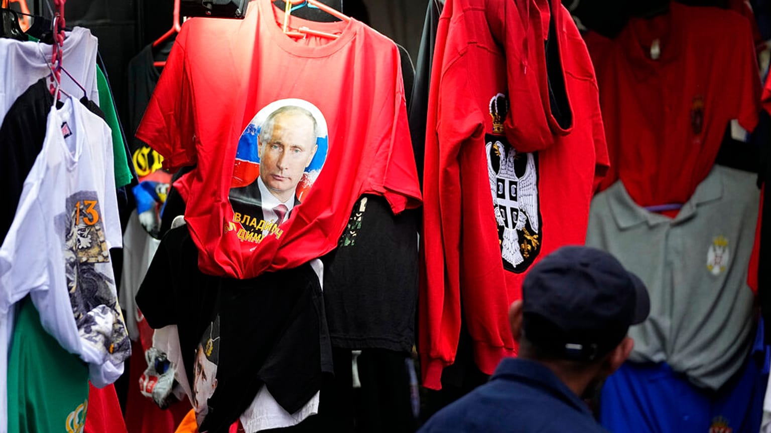 A man looks at a shirt with a picture of Russian President Vladimir Putin displayed on Belgrade's main pedestrian street, Serbia, Saturday, Feb. 26, 2022.