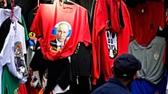 A man looks at a shirt with a picture of Russian President Vladimir Putin displayed on Belgrade's main pedestrian street, Serbia, Saturday, Feb. 26, 2022.