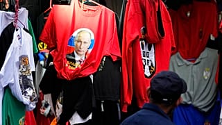 A man looks at a shirt with a picture of Russian President Vladimir Putin displayed on Belgrade's main pedestrian street, Serbia, Saturday, Feb. 26, 2022.