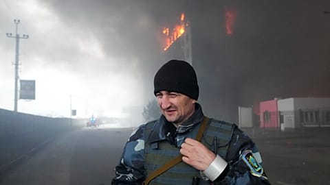 A Ukrainian serviceman walks as fire and smoke rise over a building following shelling in Kyiv, Ukraine, March 3, 2022. 