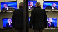 A man watches Russian President Vladimir Putin on TV screens in an electronic hypermarket in Moscow,, 2014