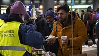 Varios refugiados reciben bebidas y alimentos calientes en la principal estación de tren de Berlín. 3 de marzo de 2022