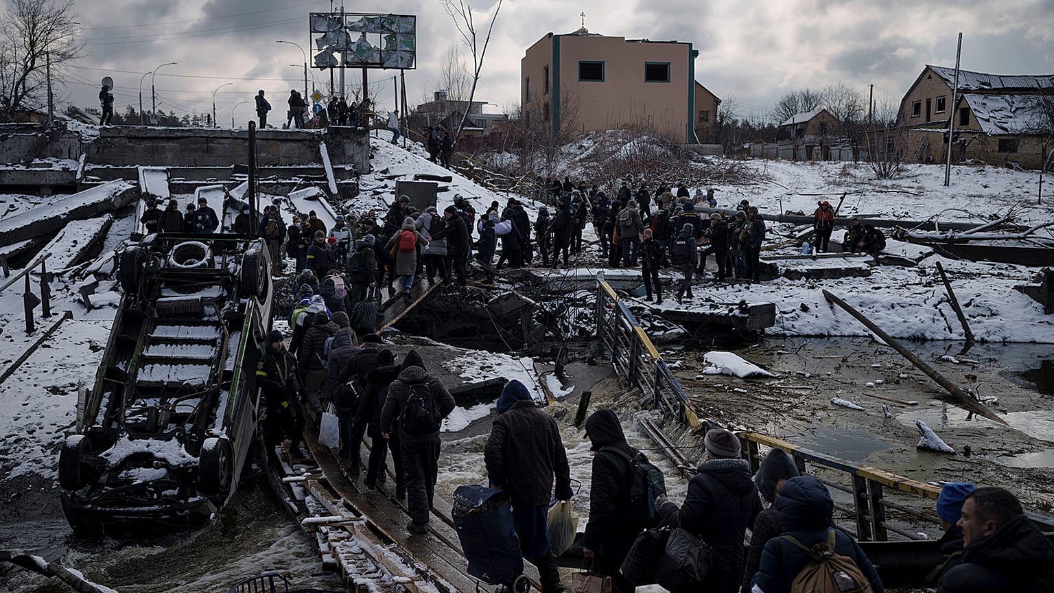 Ukrainians cross an improvised path under a destroyed bridge while fleeing Irpin, in the outskirts of Kyiv