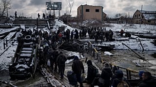 Ukrainians cross an improvised path under a destroyed bridge while fleeing Irpin, in the outskirts of Kyiv