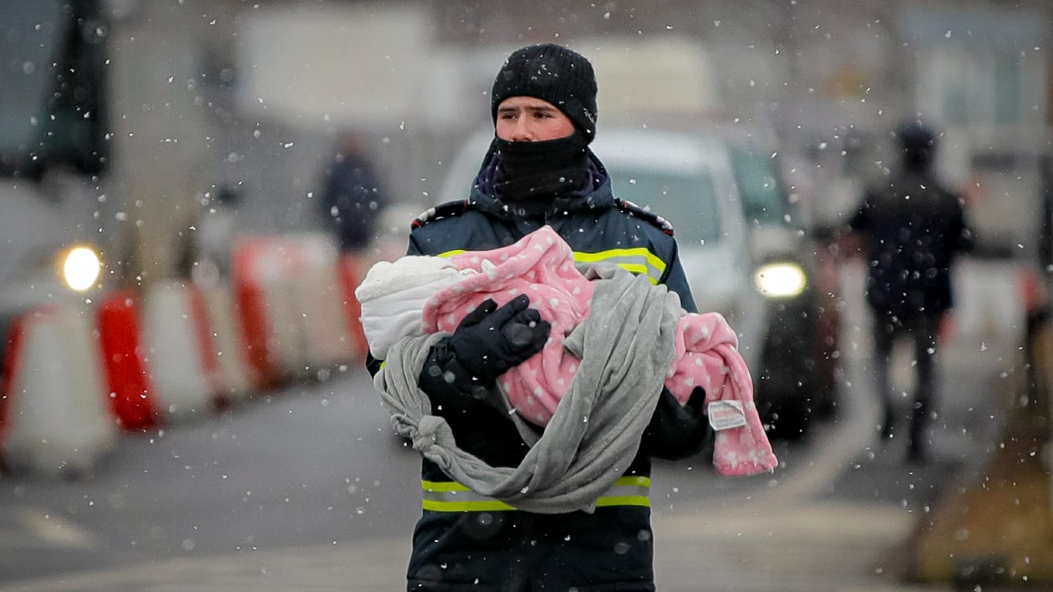 A firefighter holds the baby of a refugee fleeing the conflict from neighboring Ukraine at the Romanian-Ukrainian border, in Siret, Romania, Monday, March 7, 2022. 