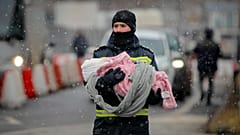 A firefighter holds the baby of a refugee fleeing the conflict from neighboring Ukraine at the Romanian-Ukrainian border, in Siret, Romania, Monday, March 7, 2022. 