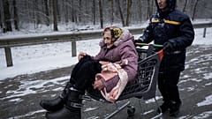 Eine Frau wird in Irpin mit Hilfe eines Einkaufswagens in Sicherheit gebracht