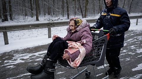 Eine Frau wird in Irpin mit Hilfe eines Einkaufswagens in Sicherheit gebracht