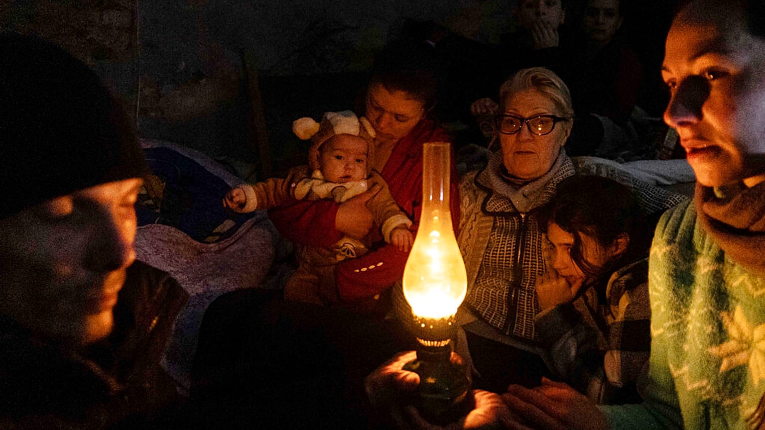 Mariupoli lakosok ülnek egy óvóhelyen március 6-án egy olajlámpa körül.