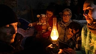 Mariupoli lakosok ülnek egy óvóhelyen március 6-án egy olajlámpa körül.