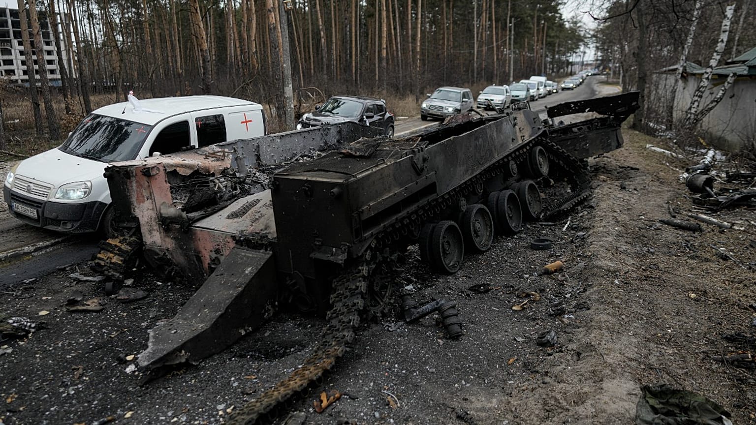 Cars drive past a destroyed Russian tank as a convoy of vehicles evacuating civilians leaves Irpin, on the outskirts of Kyiv, Ukraine, Wednesday, March 9, 2022. 