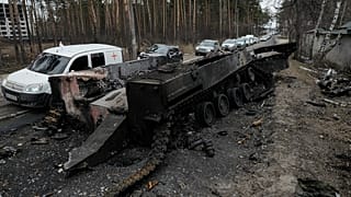 Cars drive past a destroyed Russian tank as a convoy of vehicles evacuating civilians leaves Irpin, on the outskirts of Kyiv, Ukraine, Wednesday, March 9, 2022. 