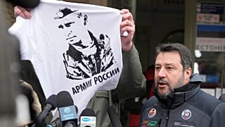 Przemysl's mayor Wojciech Bakun holds up a t-shirt with the likeness of Russian President Vladimir Putin and the words "The Russian Army" as he stands alongside Matteo Salvini