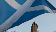 A Scottish Saltire flag blows in the wind near the Wallace Monument, Stirling, Scotland.