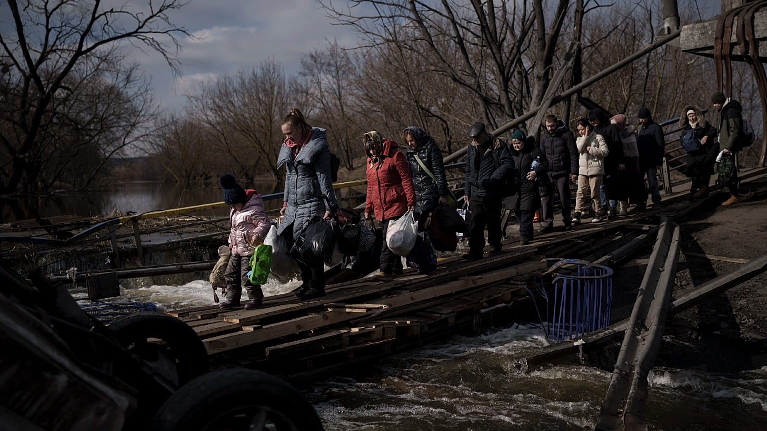 Ukrainians cross an improvised path under a destroyed bridge while fleeing Irpin, on the outskirts of Kyiv, Ukraine, Wednesday, March 9, 2022. 