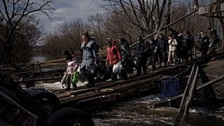Ukrainians cross an improvised path under a destroyed bridge while fleeing Irpin, on the outskirts of Kyiv, Ukraine, Wednesday, March 9, 2022.