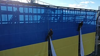 Kletterer installieren ukrainische Riesenflagge auf dem Dach des LTV-Gebäudes in Riga