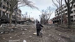 A man walks with a bicycle in a street damaged by shelling in Mariupol, Ukraine, Thursday, March 10, 2022