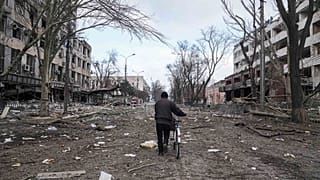 A man walks with a bicycle in a street damaged by shelling in Mariupol, Ukraine, Thursday, 10 March , 2022. 