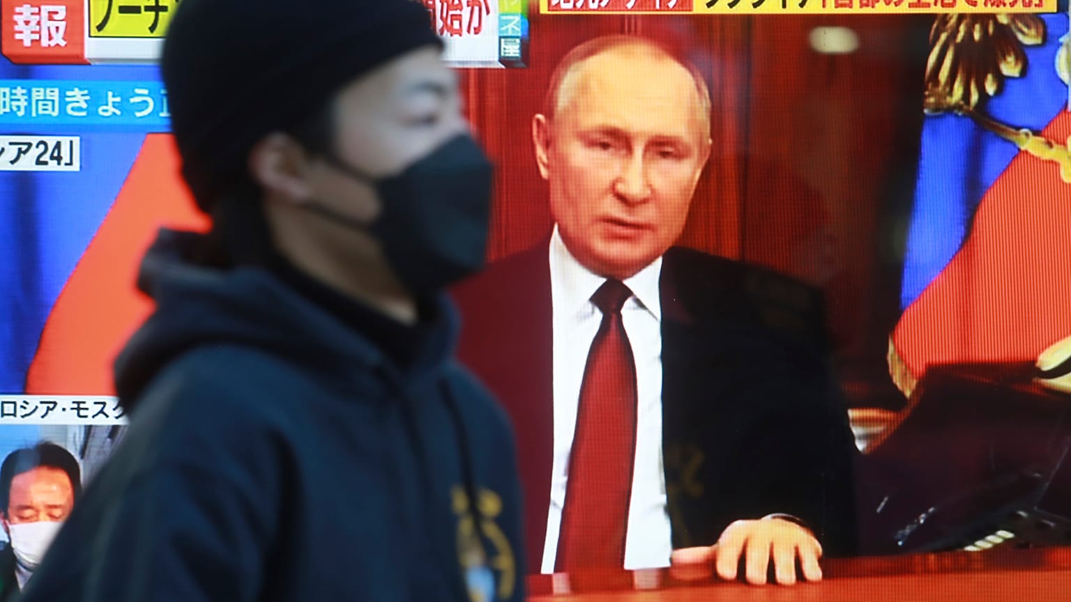 A man walks past a TV screen with image of Russia's President Vladimir Putin in Tokyo, Thursday, Feb. 24, 2022.
