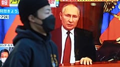 A man walks past a TV screen with image of Russia's President Vladimir Putin in Tokyo, Thursday, Feb. 24, 2022.