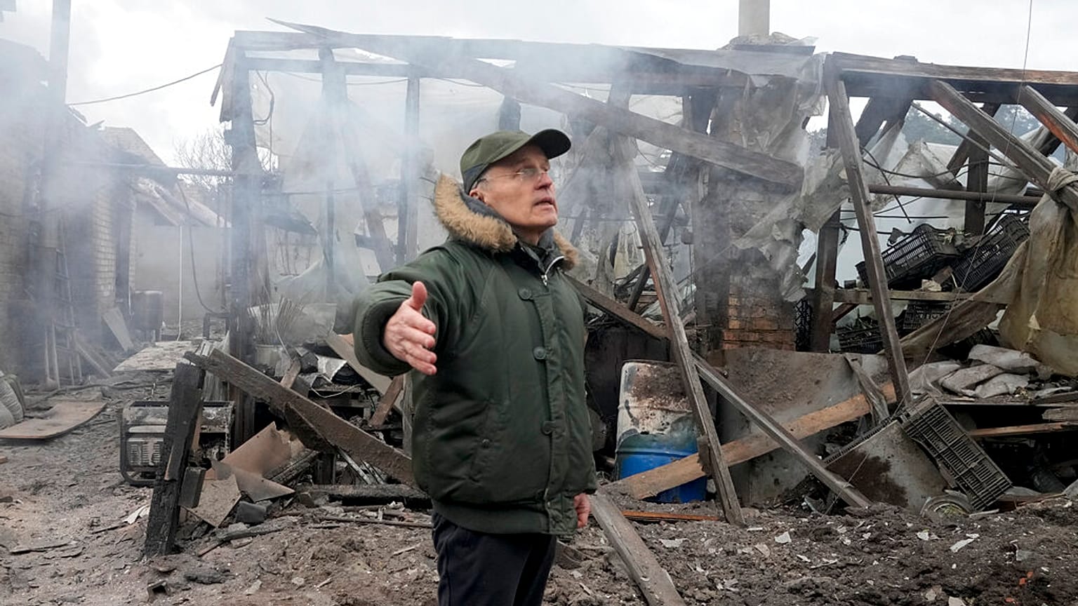A man opens his arms as he stands near a house destroyed in the Russian artillery shelling, in the village of Horenka close to Kyiv