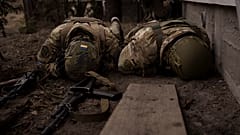 Des soldats se couvrent de tirs d'artillerie à Irpin dans les faubourds de Kyiv, le 13 mars 2022