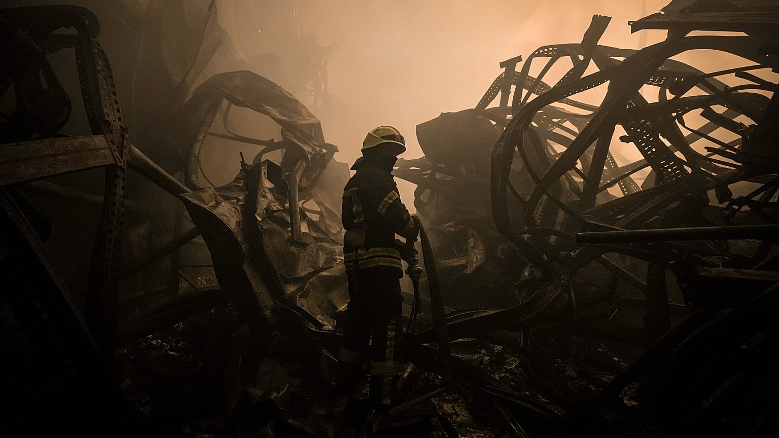 Un pompier ukrainien tire une lance à incendie dans un entrepôt de nourriture bombardé par les forces Russes dans les faubourgs de Kyiv, le 13 mars 2022