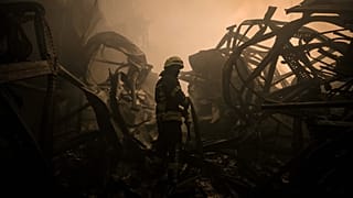 Un pompier ukrainien tire une lance à incendie dans un entrepôt de nourriture bombardé par les forces Russes dans les faubourgs de Kyiv, le 13 mars 2022