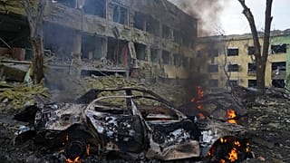 Egy autó ég a lebombázott mariupoli szülészet előtt