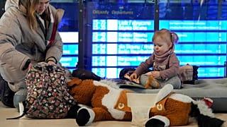 Une jeune femme joue avec une petite fille assise sur un matelas gonflable dans la gare de Varsovie, le 13 mars 2022