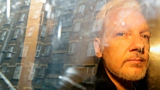 FILE - In this Wednesday May 1, 2019 file photo buildings are reflected in the window as WikiLeaks founder Julian Assange is taken from court in London.