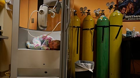 A 6-year-old girl curls up in the plethysmography chamber during a break in her pulmonary function test at Children's National Hospital, in Washington, Jan. 26, 2022.