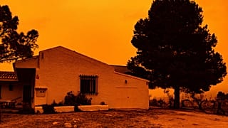 An orange sky is seen over a building in Navares, south eastern Spain on Monday.