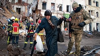 A volunteer of the Ukrainian Territorial Defense Forces assists a woman to cross the street in Kharkiv, Ukraine, Wednesday, March 16, 2022.