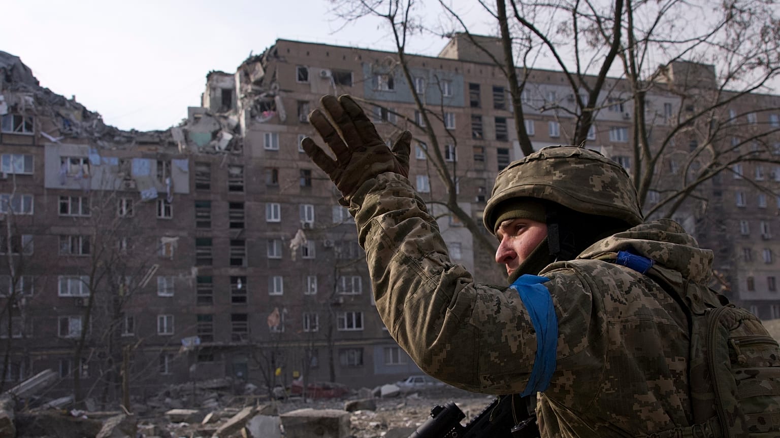 Soldado ucraniano perante edifício destruído em Mariupol