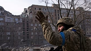 Soldado ucraniano perante edifício destruído em Mariupol