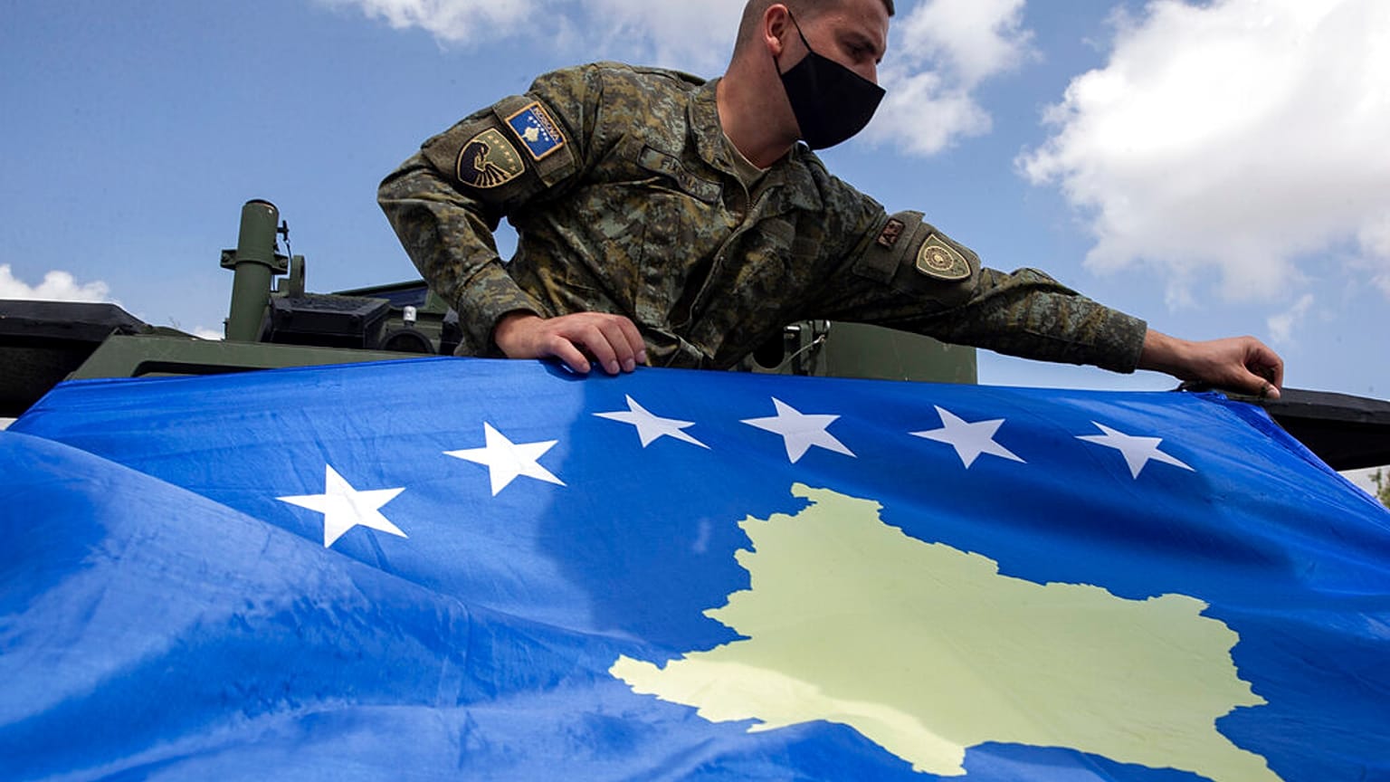 Kosovo Security Force soldier places a Kosovo flag on top of armored security vehicle donated by U.S during a handout ceremony in the military barracks Adem Jashari.