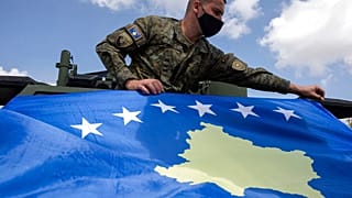 Kosovo Security Force soldier places a Kosovo flag on top of armored security vehicle donated by U.S during a handout ceremony in the military barracks Adem Jashari.