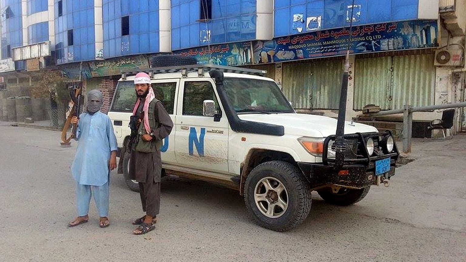 مقاتلو طالبان يلتقطون صورة بجوار مركبة تابعة للأمم المتحدة في قندوز بأفغانستان.