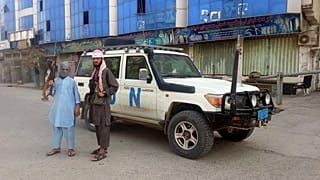 مقاتلو طالبان يلتقطون صورة بجوار مركبة تابعة للأمم المتحدة في قندوز بأفغانستان.