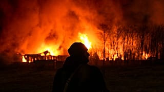 Un militaire ukrainien à l'arrière d'un entrepôt en feu après une frappe dans la banlieue de Kiev, jeudi 17 mars 2022.