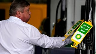 A driver grabs a fuel nozzle at a petrol station to fill up his car in London, Monday, Oct. 4, 2021.