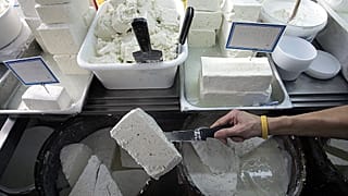 A shop assistant lifts a slab of feta cheese in Athens.