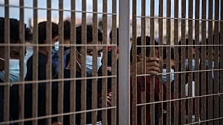 لاجئون من الشرق الأوسط، عبروا البحر الأبيض المتوسط  خلف سياج في لامبيدوزا، إيطاليا. 
