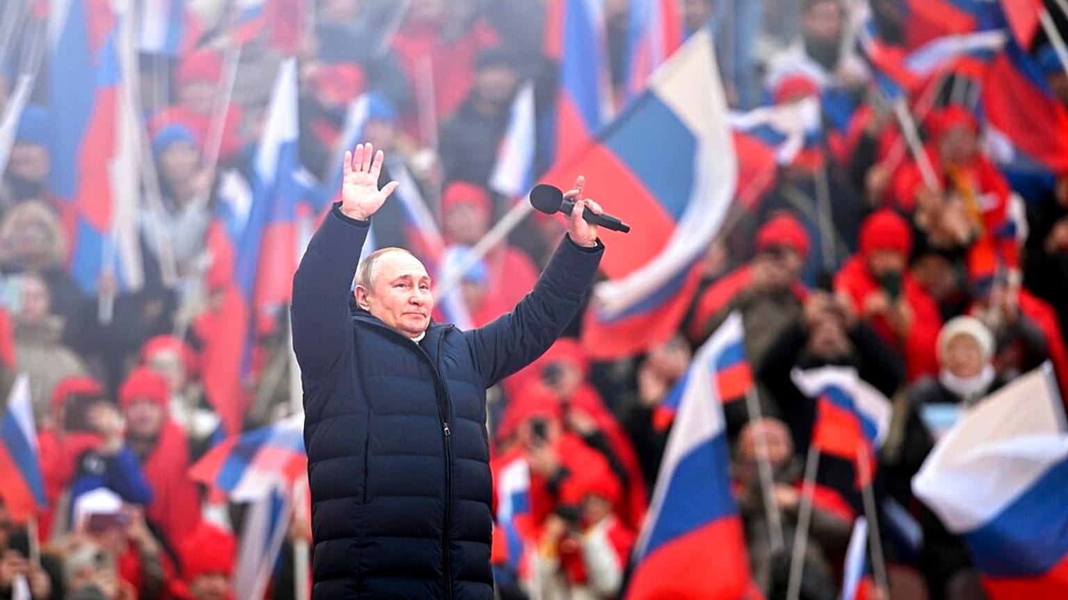 Vladimir Poutine salue la foule après son discours au stade olympique de Moscou, le 18 mars 2022