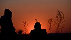 Ukrainian evacuees wait for relocation as the sun goes down after crossing the Ukrainian-Romanian border in Siret, northern Romania