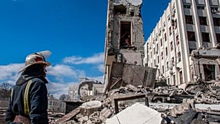 Διασώστης μπροστά σε χαλάσματα κυβερνητικού κτιρίου στο Χάρκοβο της Ουκρανίας