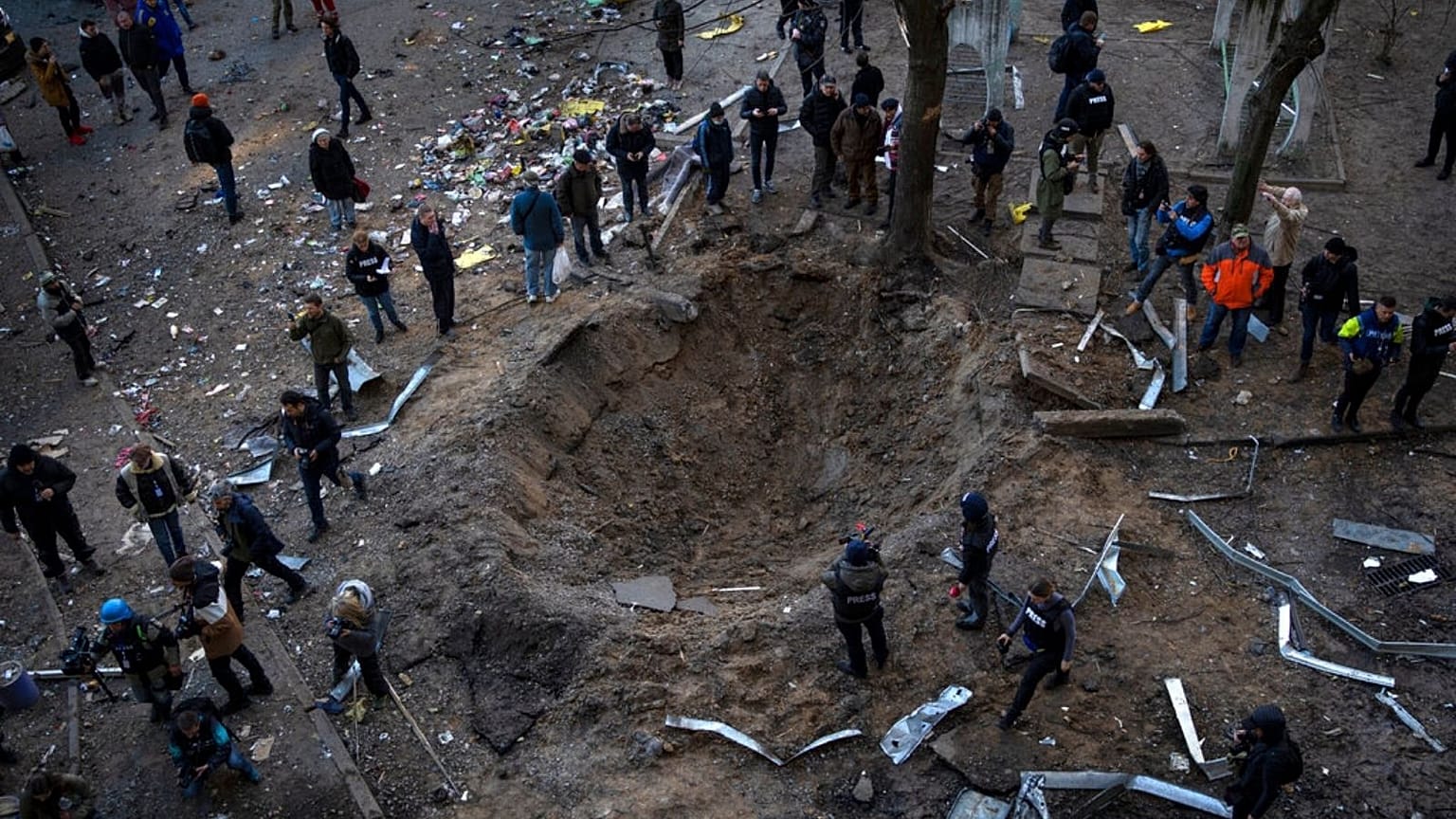 a crater created by a bomb that heavily damaged buildings and cars in Kyiv